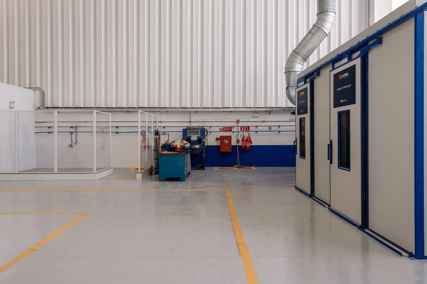 Área técnica industrial com cabine e sistema de exaustão executados pela Tektos